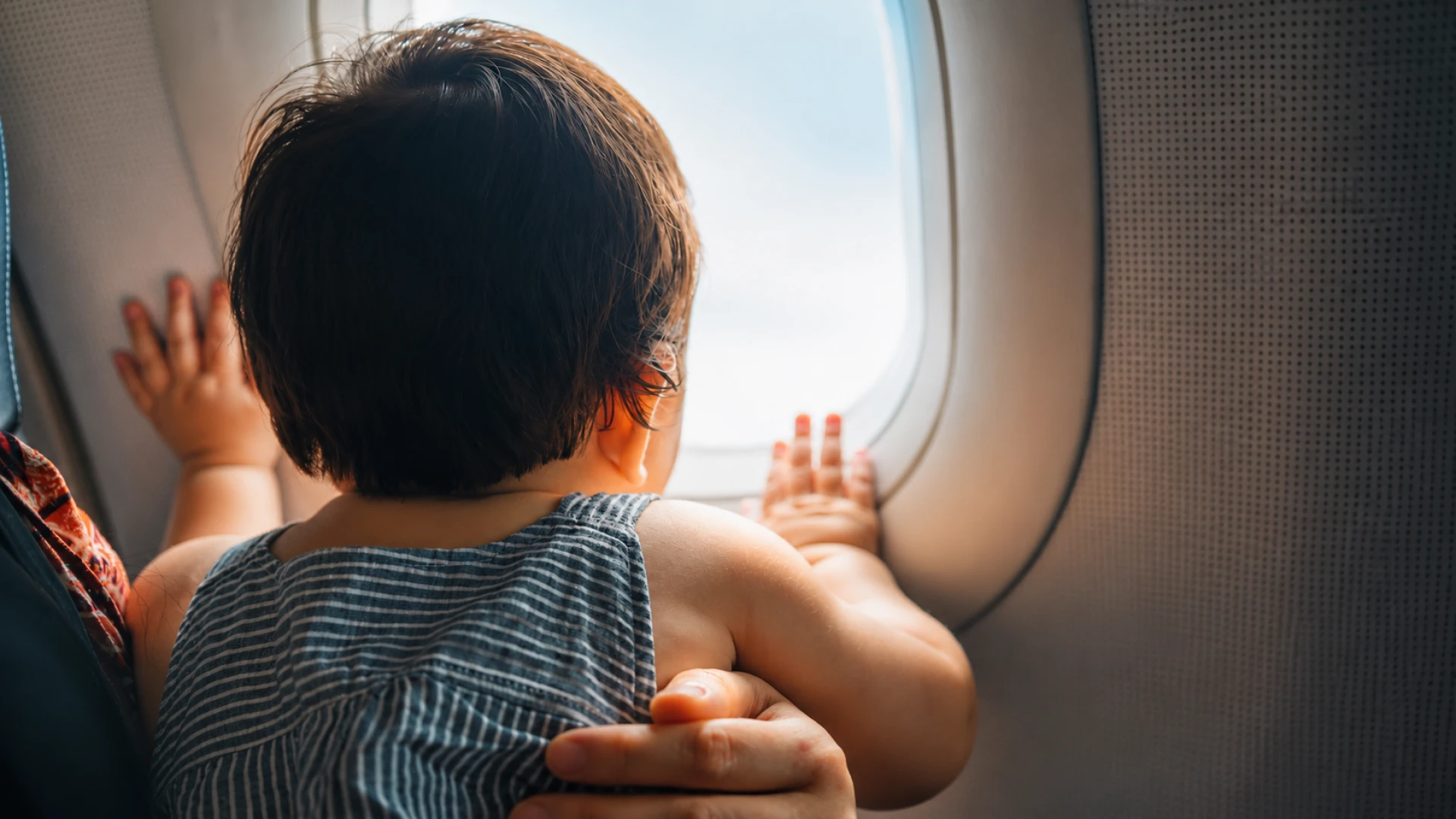 Kleinkind blickt während eines Flugs aus dem Flugzeugfenster